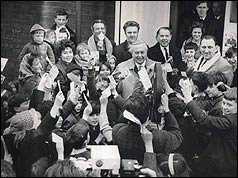 Harold Wilson surrounded by children waving leaflets 