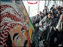 Ceremony to award cheques under a painting of Arafat and Saddam