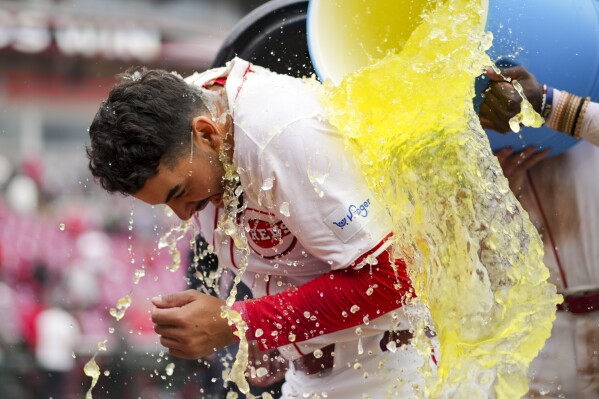 Cincinnati Reds' Christian Encarnacion-Strand is doused by teammates after hitting a game-winning solo home run during the ninth inning of a baseball game against the Washington Nationals in Cincinnati, Sunday, March 31, 2024. (AP Photo/Aaron Doster)