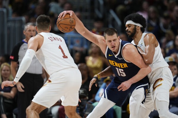 Denver Nuggets center Nikola Jokic, center, drives to the basket between Cleveland Cavaliers guard Max Strus, left, and center Jarrett Allen in the first half of an NBA basketball game, Sunday, March 31, 2024, in Denver. (AP Photo/David Zalubowski)