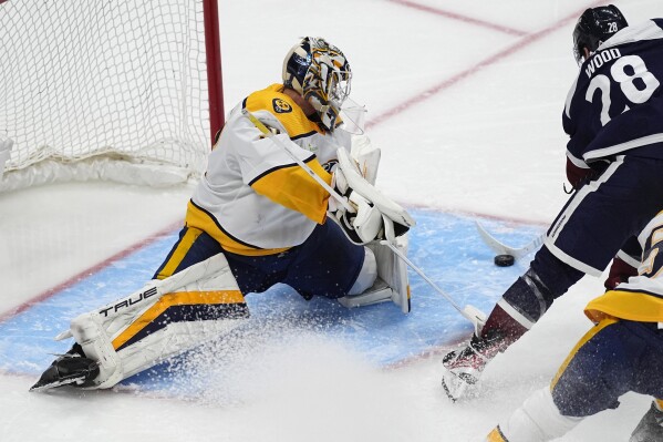 Nashville Predators goaltender Kevin Lankinen, left, looks to stop a shot by Colorado Avalanche left wing Miles Wood during the third period of an NHL hockey game Saturday, March 30, 2024, in Denver. (AP Photo/David Zalubowski)