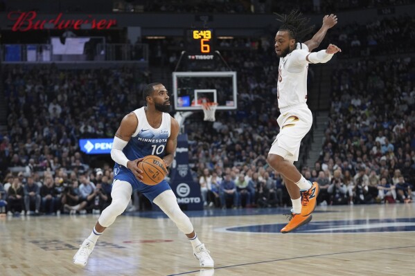Minnesota Timberwolves guard Mike Conley (10) looks to shoot as Cleveland Cavaliers guard Darius Garland defends during the first half of an NBA basketball game Friday, March 22, 2024, in Minneapolis. (AP Photo/Abbie Parr)