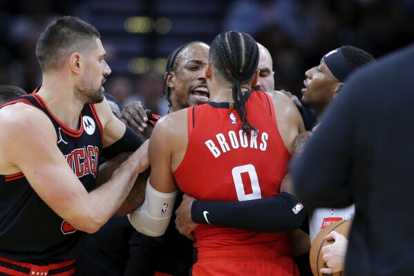 Chicago Bulls forward DeMar DeRozan, center left, and Houston Rockets forward Dillon Brooks, center right, are held back from each other during a scuffle that ensued after DeRozan's flagrant foul against Rockets' Jale Green during the second half of an NBA basketball game Thursday, March 21, 2024, in Houston. Both DeRozan and Brooks were charged with technical fouls and ejected from the game. (AP Photo/Michael Wyke)