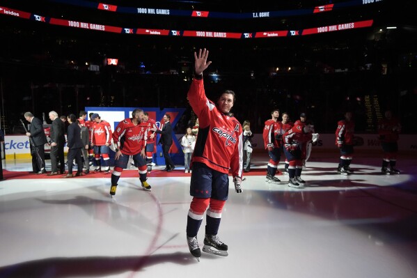 Washington Capitals right wing T.J. Oshie, center, acknowledges the crowd during a ceremony to mark his playing in 1000 career NHL games before an NHL hockey game against the Winnipeg Jets, Sunday, March 24, 2024, in Washington. (AP Photo/Mark Schiefelbein)