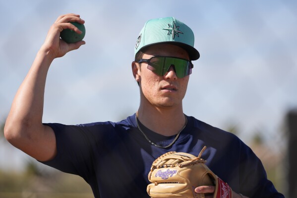 FILE - Seattle Mariners starting pitcher Bryan Woo warms up during spring training baseball workouts, Feb. 15, 2024, in Peoria, Ariz. The Mariners will start the season with Woo on the 15-day injured list due to inflammation in his right elbow. (AP Photo/Lindsey Wasson, File)