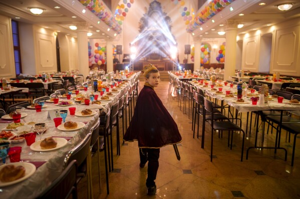 A child of the Ukrainian Jewish community, walks between tables set for Purim celebrations before a festive meal at the Great Choral Synagogue in Kyiv, Ukraine, Sunday, March 24, 2024. (AP Photo/Vadim Ghirda)