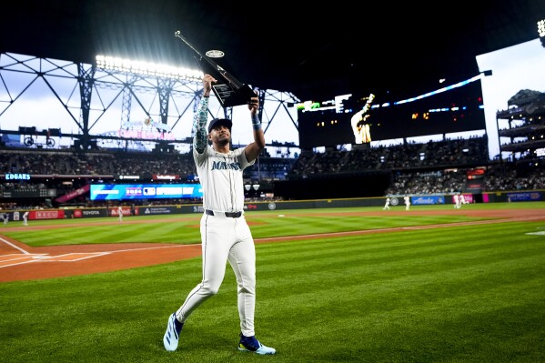 Seattle Mariners center fielder Julio Rodríguez holds up his Silver Slugger award for last season, after a presentation before the team's opening-day baseball game against the Boston Red Sox, Thursday, March 28, 2024, in Seattle. (AP Photo/Lindsey Wasson)