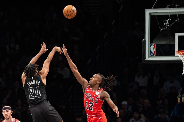 Brooklyn Nets guard Cam Thomas (24) shoots over Chicago Bulls' Ayo Dosunmu (12) during the first half of an NBA basketball game in New York, Friday, March 29, 2024. (AP Photo/Peter K. Afriyie)