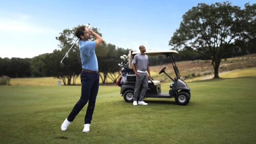 a man swings a golf club on golf course