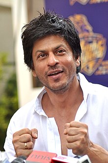 Shah Rukh Khan in a white shirt is interacting with the media