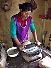 Isabel Nicolás, a Ñuu Savi (Mixtec) woman grinding corn dough in the yooso (metate in Mixtec) when making tortillas. San Juan Achiutla, Oaxaca, México, 2020.