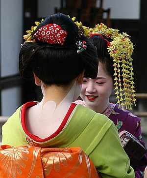2 Maiko (aprendiz de gueixa) conversando perto do Templo de Ouro em Kyoto, Japão. Partes do kimono e a especial maquiagem são claramente visíveis
