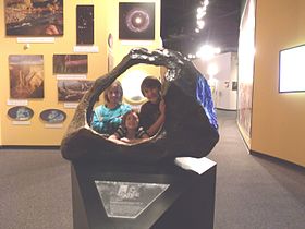 Crianças posando atrás do Meteorito Tucson Ring no Museu de História Natural do Arizona, Estados Unidos
