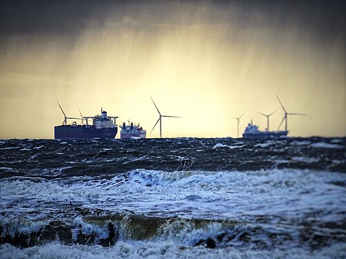 Boats, waves and wind turbines share the horizon in Katwijk Aan Zee, NL.