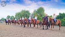 Photo montrant des cavaliers en tenue traditionnelle alignés sur un terrain sableux