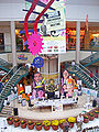Photo d'intérieur d'un centre commercial présentant une exposition avec des affiches de la série et des fabrications en papier des personnages.