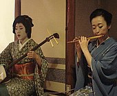 Two geikos playing the shamisen and the shinobue.