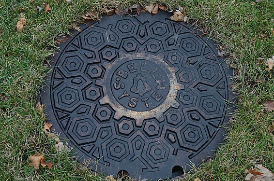 An old Bell System manhole cover during a rainy day