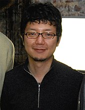 Uma fotografia de um homem japonês usando óculos.