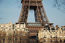 Photographie montrant le second étage de la tour Eiffel dominant le toit des immeubles environnants.