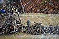 Residents cross a river after the bridge is washed out