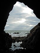 Photographie de l’ouverture d’une grotte sur la mer, vue du fond de la grotte.