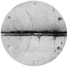 track of subatomic particle moving upward through cloud chamber and bending left (an electron would have turned right)