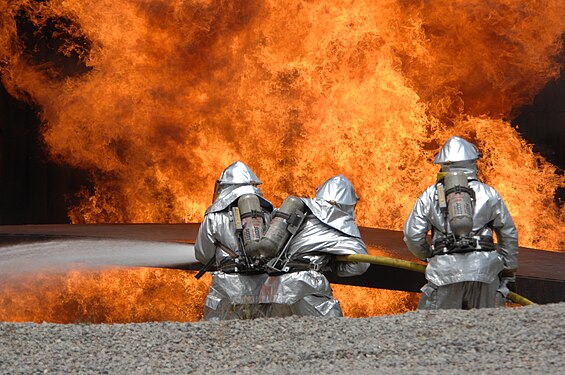 ثلاثة رجال من القُوَّات الجويَّة الأمريكيَّة، في دورة ميدانية لإطفاء ومكافحة الحرائق