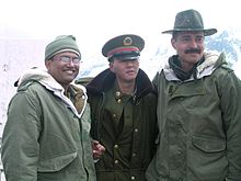 Deux soldats indiens enserrant de part et d'autre, et par-delà un fil barbelé, un soldat chinois en uniforme.