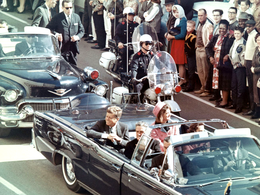 Tổng thống Kennedy cùng vợ Jacqueline, ngồi phía sau thống đốc bang Texas John Connally và vợ của ông Nellie, trên đoàn xe hộ tống tổng thống, vài phút trước khi vụ ám sát xảy ra.