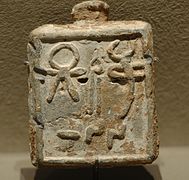 Pesa col símbolu de la diosa fenicia Tanit. Topáu na islla de Llabraos (Siria).