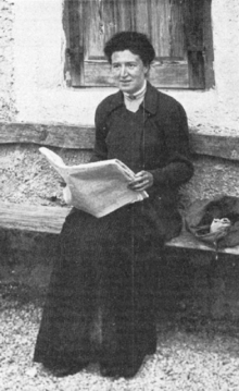 Photograph of a woman sitting and reading a newspaper