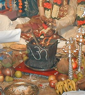 Throwing offerings on the fire, lit in a box with a Devanagari "Aum" written on it, during a Hindu wedding.
