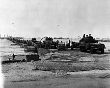 Kjøretøy fra U.S. Army kjører over kunstig havn, Omaha Beach, 16. juni (stor versjon)