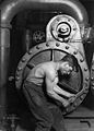 Image 43Lewis Hine's 1920 image "Power house mechanic working on steam pump," which shows a working class young American man with wrench in hand, hunched over, surrounded by the machinery that defines his work.