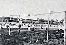 Photo d'un terrain de football pendant un match, vu depuis derrière un but.