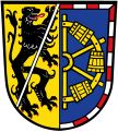 Landkreis Erlangen-Höchstadt Gespalten; vorne in Gold ein linksgewandter, mit einer silbernen Schräglinksleiste überdeckter, rot bewehrter schwarzer Löwe; hinter in Blau mit von Rot und Silber gestücktem Bord, ein halbes goldenes Wasserschöpfrad.