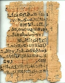 黒と赤のインクでヒエラティックの手書き文字が書かれた、裂けて断片化した古いパピルス文書