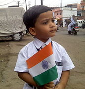 हातात राष्ट्रीय ध्वज घेणारा लहान मुलगा