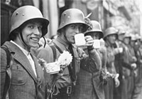 Homens do Corpo de Volutários Alemães dos Sudetos recebem flores e bebidas quentes da população local, em Eger (3 de outubro de 1938).