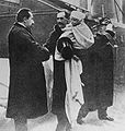 Kong Haakon kjem til Noreg 25. november 1905 med kronprins Olav på armen. Statsminister Christian Michelsen ynskjer den nye kongen velkomen.