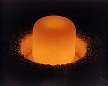 Silinder bercahaya dari plutonium oksida berdiri di biji melingkar