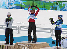 Vue de loin de trois femmes sur le podium, la première levant les bras en l'air.