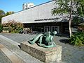Der Haupteingang zum Ausstellungsgebäude der Akademie der Künste am Berliner Hanseatenweg. Im Vordergrund die Skulptur „Die Liegende“ von Henry Moore