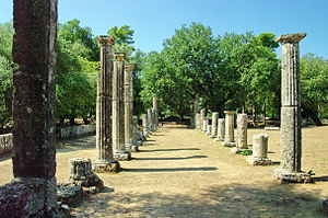 Greeksche Pillare, Böme in’n Achtergrund. Dar twischen dat Sandfeld, wo de Athleten traineren