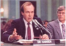 James Hansen speaking into a microphone while seated in Congress.