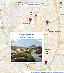 Screenshot of a map in full size view. There are some round markers in grey and some markers in red. One round marker shows a popup with a title, description and image.