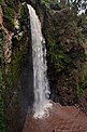 Ein einstufiger Wasserfall an einer felsigen Klippe mit einem schlammbraunen Wasserbecken