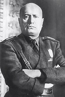 official portrait of Mussolini in uniform with crossed arms