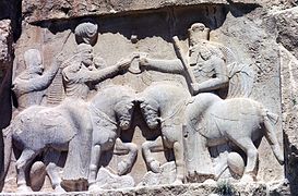 Invistidura d'Ardacher I (fundador de la dinastía sasánida, nel sieglu III) pol dios Ahura Mazda. Los sos caballos apatayen al anterior rei, Artabán IV, y a la deidá negativa Ahriman. Naqsh i Rustam.
